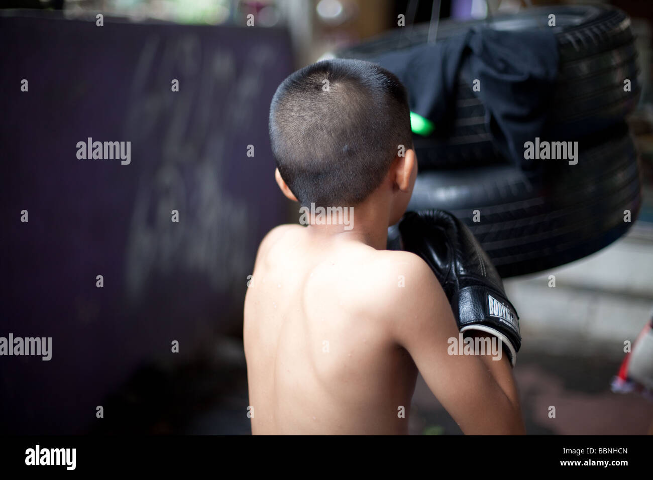 Junge skinny Muay thai Boxer Züge mit Reifen in einem Slum Camp leichte Bewegungsunschärfe mit Einfrieren flash Stockfoto
