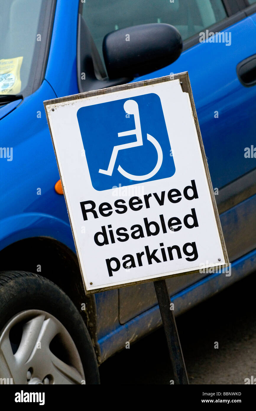 Reservierte Behinderten Parkplatz Schild neben blaues Auto im Parkhaus Stockfoto