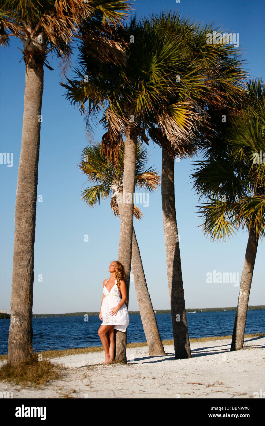 Weiße blonde barfuß Frau Entspannung am Strand auf einer tropischen Insel an eine Palme gelehnt. Stockfoto