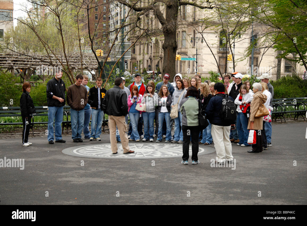 Eine Menge von Touristen um das Imagine-Mosaik in Strawberry Fields, Central Park in New York mit den Dakota Gebäude hinter. Stockfoto