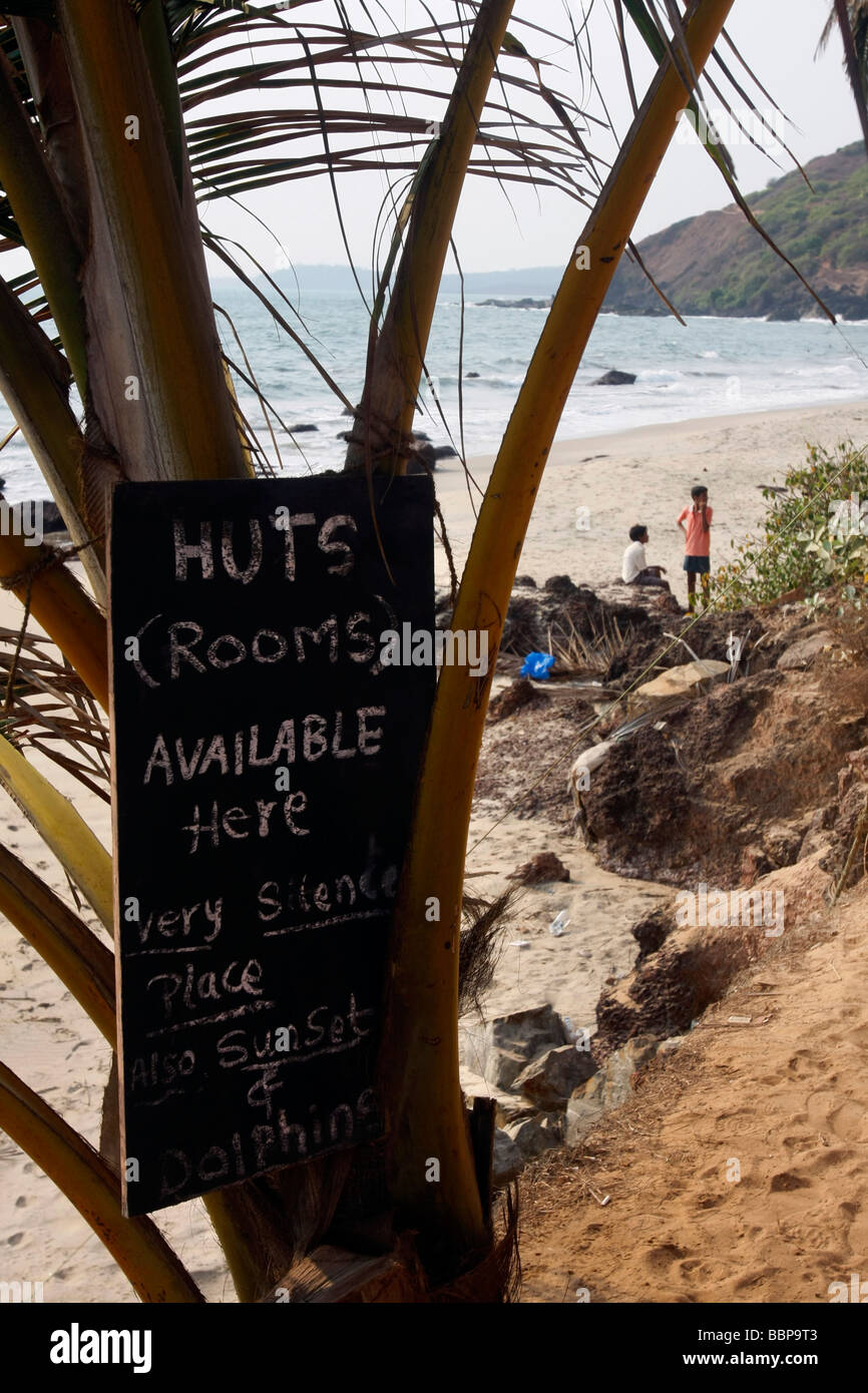 Ein Brett werben für billige Beherbergungsbetriebe in einfachen Hütten am Strand von Arambol im nördlichen Goa in Indien Stockfoto