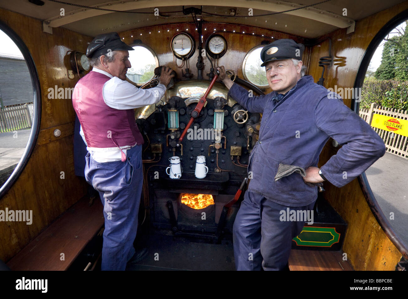 Ein Lokführer und Feuerwehrleute an der Bluebell Railway, eine erhaltene Bahnstrecke in Sussex, England. Stockfoto