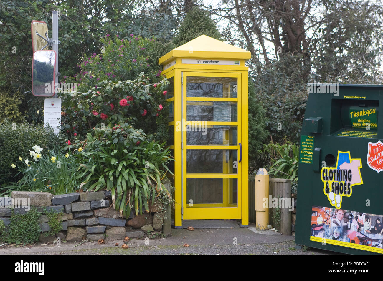 Eine gelbe Telefonzelle neben einem Papierkorb Stockfoto