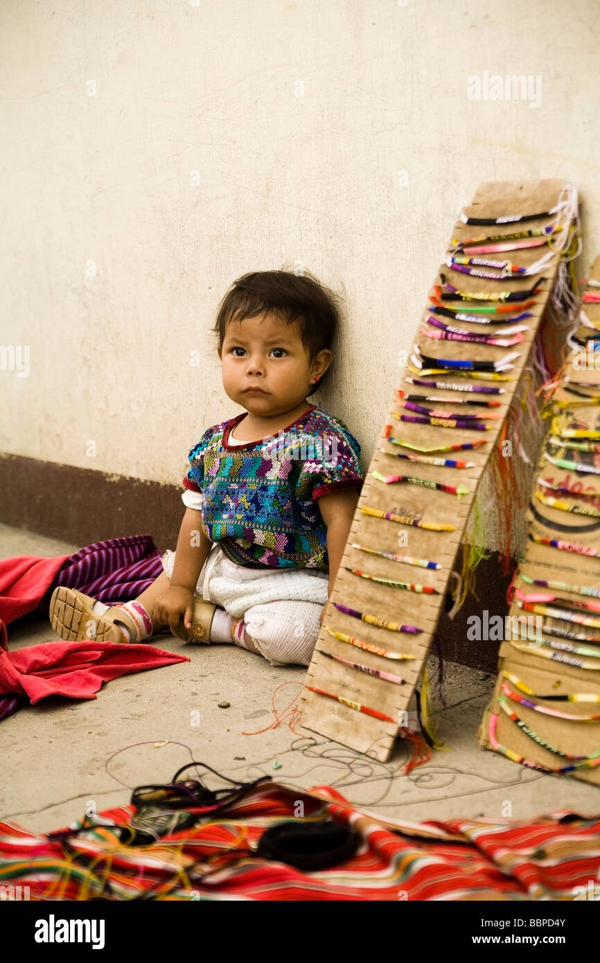 Guatemala; Babymädchen sitzt neben einer Darstellung der gewebte Armbänder,, Stockfoto