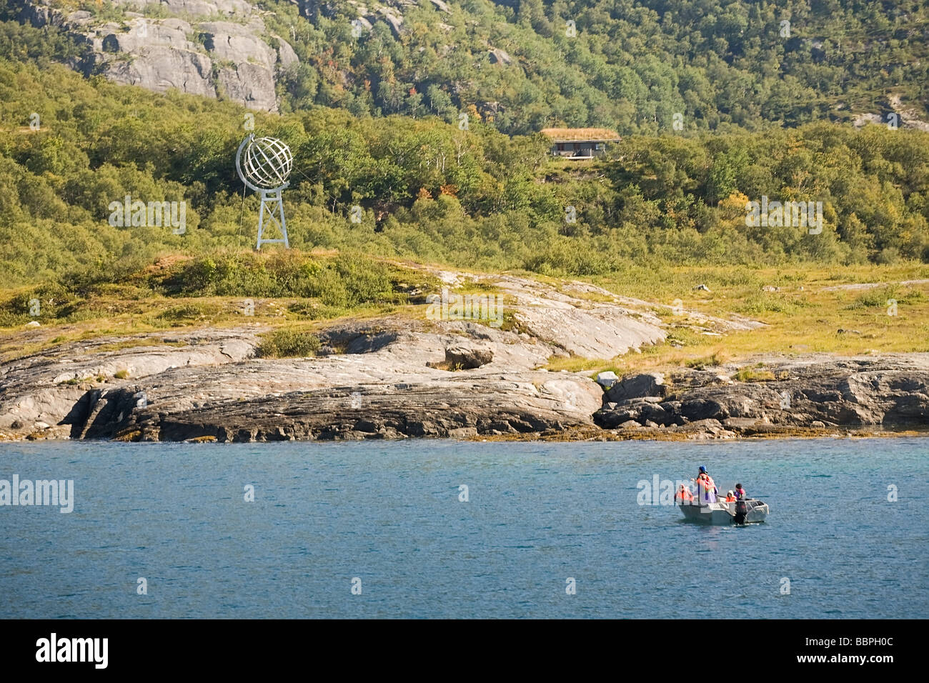 Menschen in einem Boot gegenüber hügeligen Küste Norwegens mit Polarkreis Zeichen Blick vom Meer Stockfoto