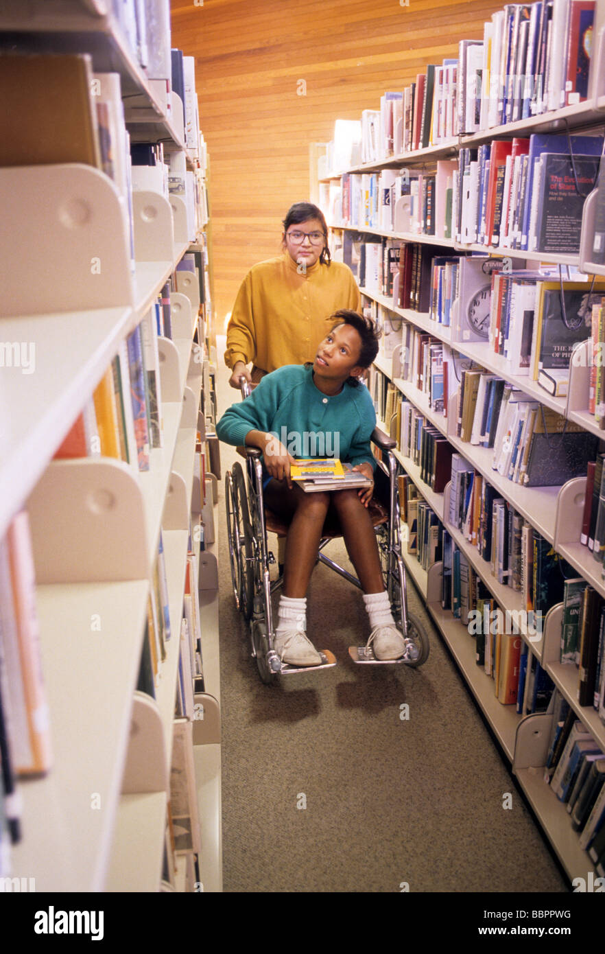 Rollstuhl Rollstuhl Handicap Mädchen Bibliothek Freund Hilfe Unterstützung helfen Buch finden wählen Sie in der Lage deaktivieren auswählen Stockfoto