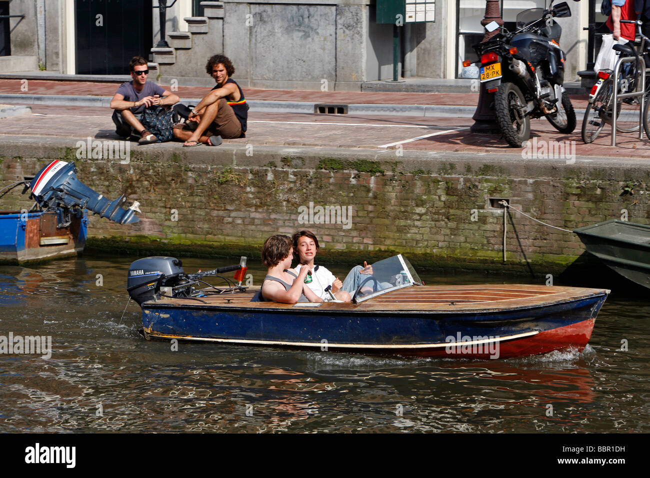 EIN AUSFLUGSSCHIFF MIT ZWEI JUGENDLICHEN TRINKEN EIN BIER AUF EINEM KANAL,  AMSTERDAM, NIEDERLANDE, HOLLAND Stockfotografie - Alamy