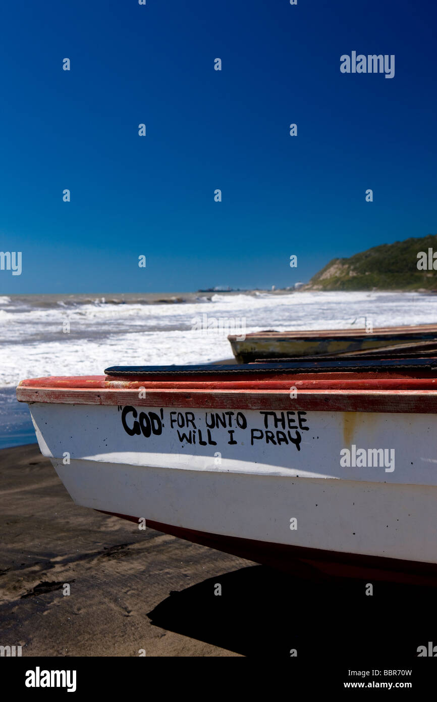 Kleines Angelboot/Fischerboot mit Religioins Text auf der Seite, festgemacht an einem karibischen Strand Stockfoto