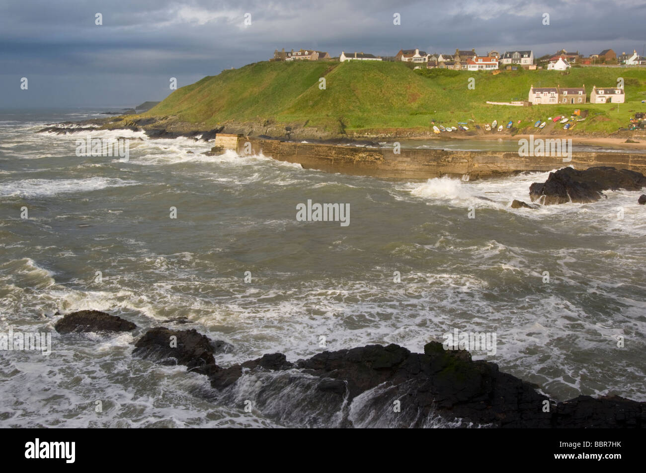 Stürmische Wellen in dem traditionellen Fischerdorf und Hafen von Stonehaven, Schottland. Die Felsen sind aus Granit. Stockfoto