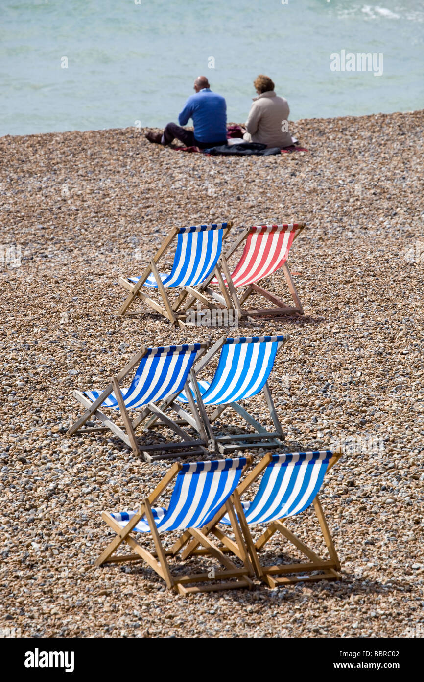 Paar am Strand neben Liegestühlen Brighton England Stockfoto