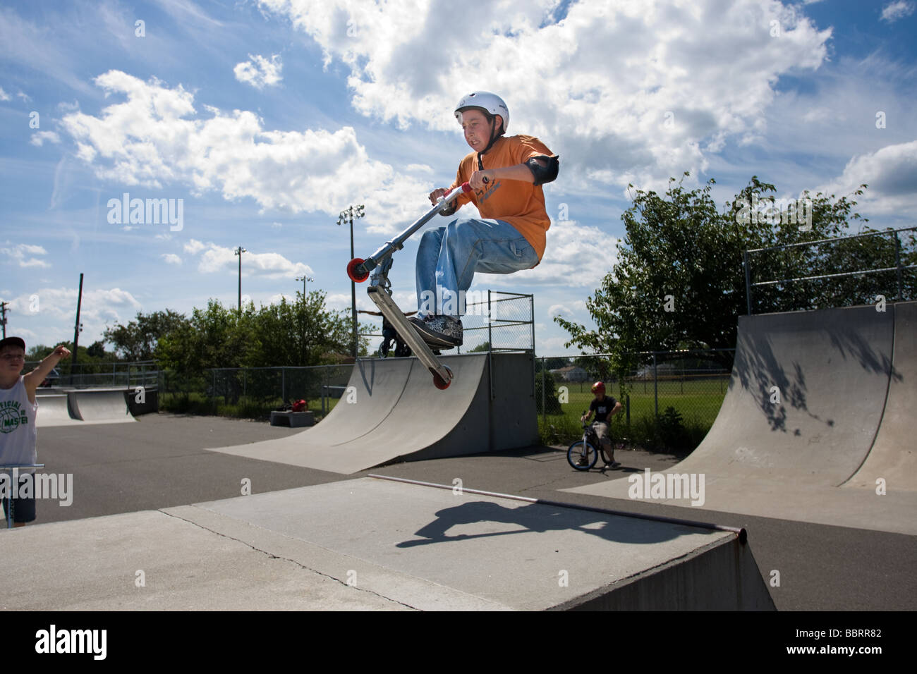 Ein kleiner Junge auf einem Roller hat einen Sprung in einem öffentlichen Skatepark in West Haven Connecticut Stockfoto