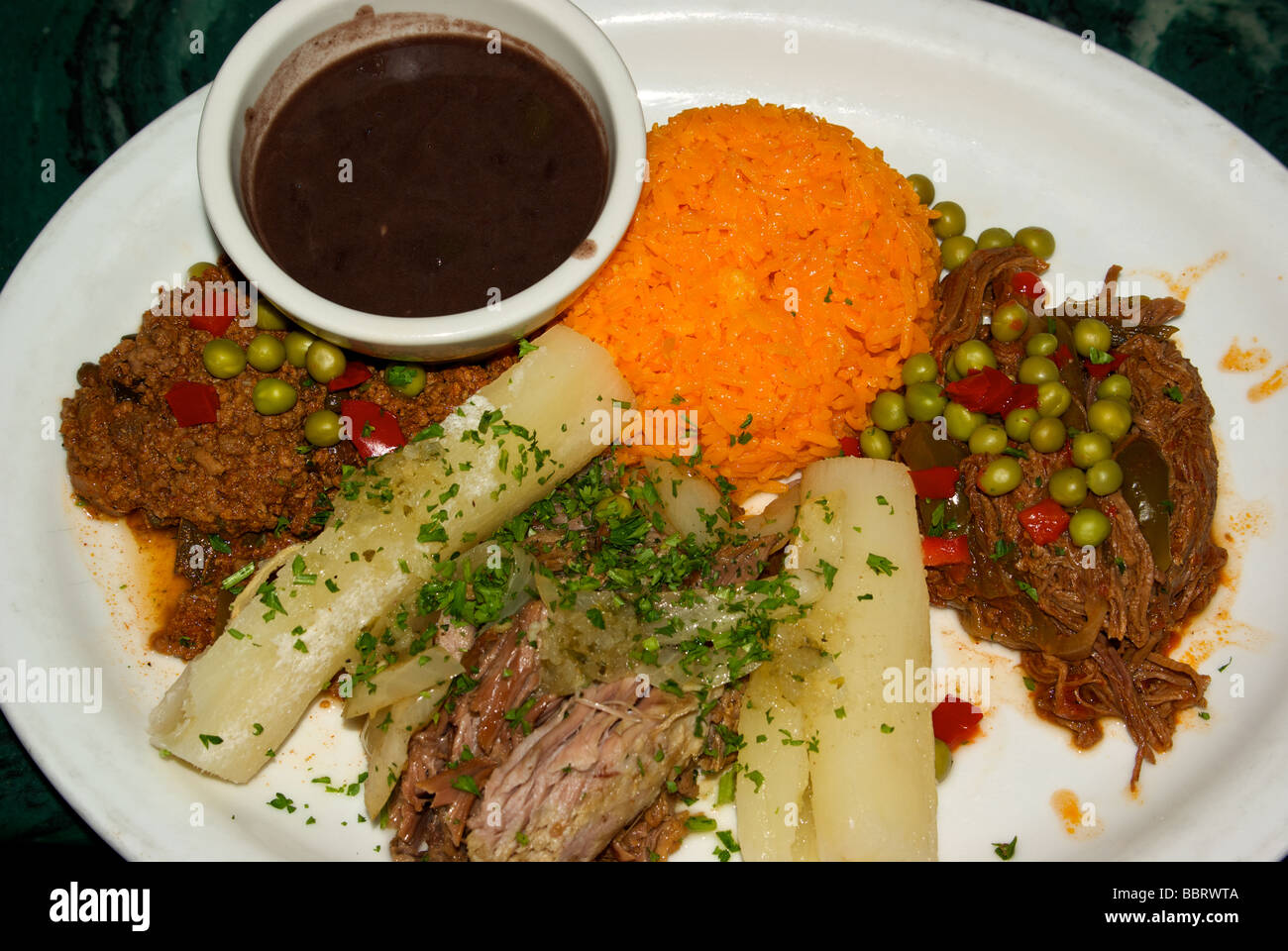 Completas drei Arten von kubanischen Stil gekocht Rindfleisch Ropa Vieja Chili Con Carne mit schwarzen Bohnen gelbem Reis Yuccawurzel Stockfoto