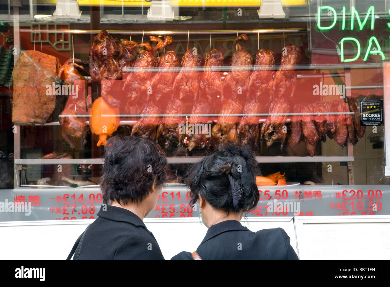 Zwei Frauen, Blick auf die Speisekarte vor einem chinesischen Restaurant in der Gerrard Street, Chinatown, London, UK Stockfoto