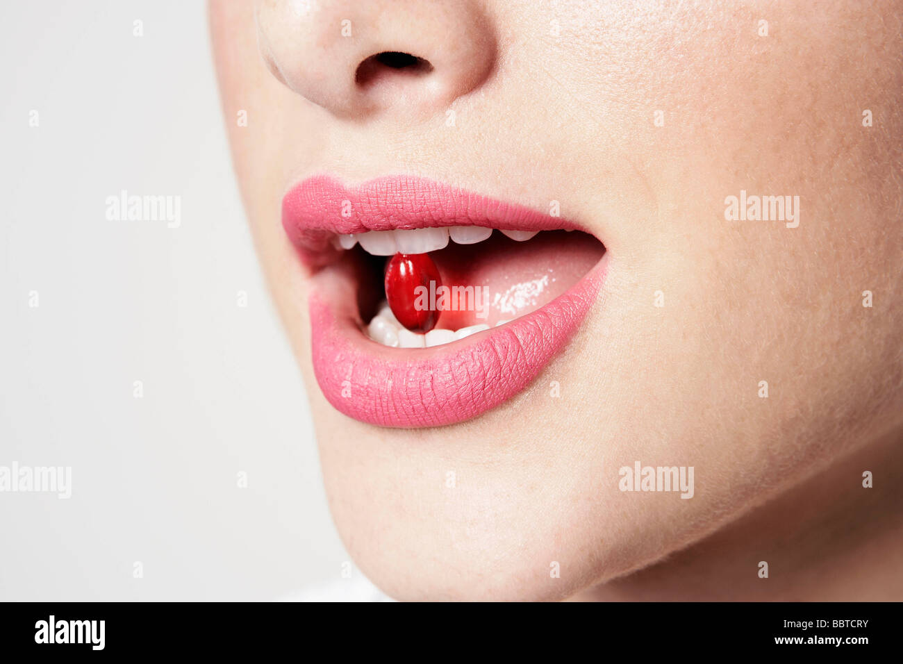 Frau mit Pille zwischen den Zähnen Stockfoto