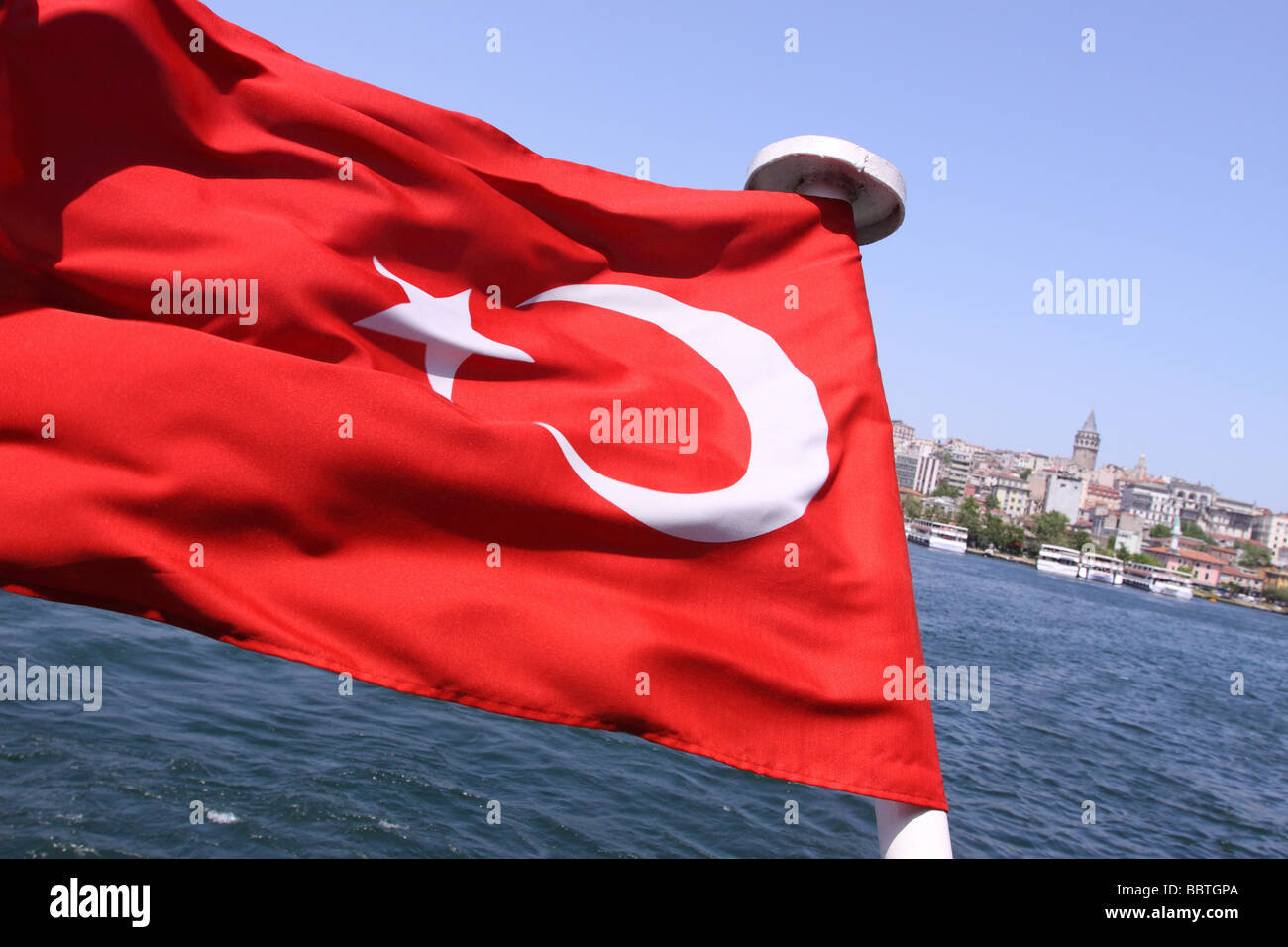 Istanbul Türkei türkische Flagge auf einer Fähre wie es das Goldene Horn mit der Galata-Turm im Hintergrund kreuzt Stockfoto