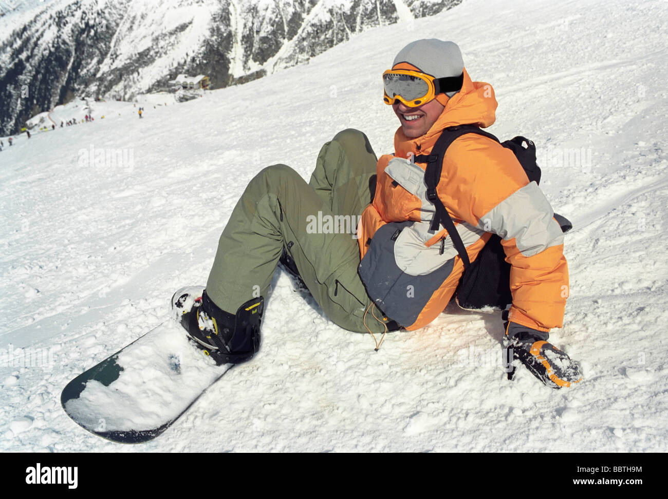 Junge sitzt im Schnee mit snowboard Stockfoto