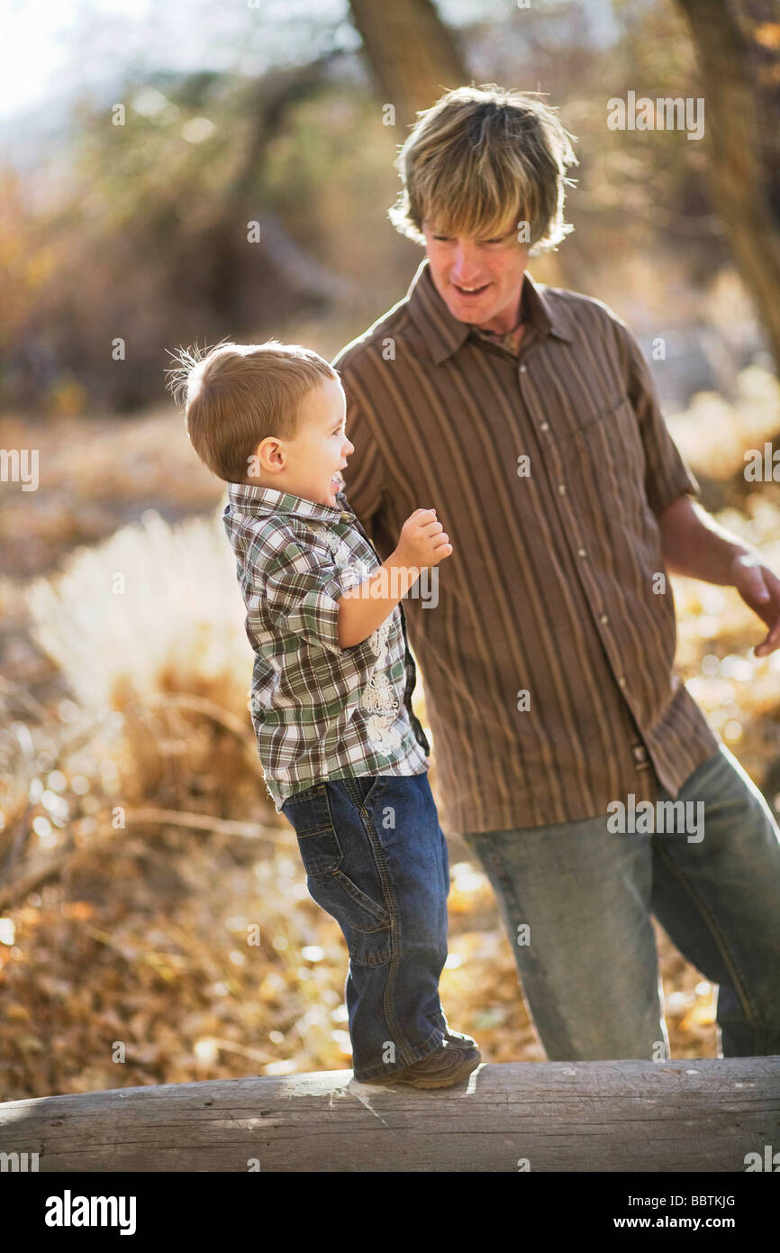 Vater Führung junger Sohn auf Baumstamm Stockfoto