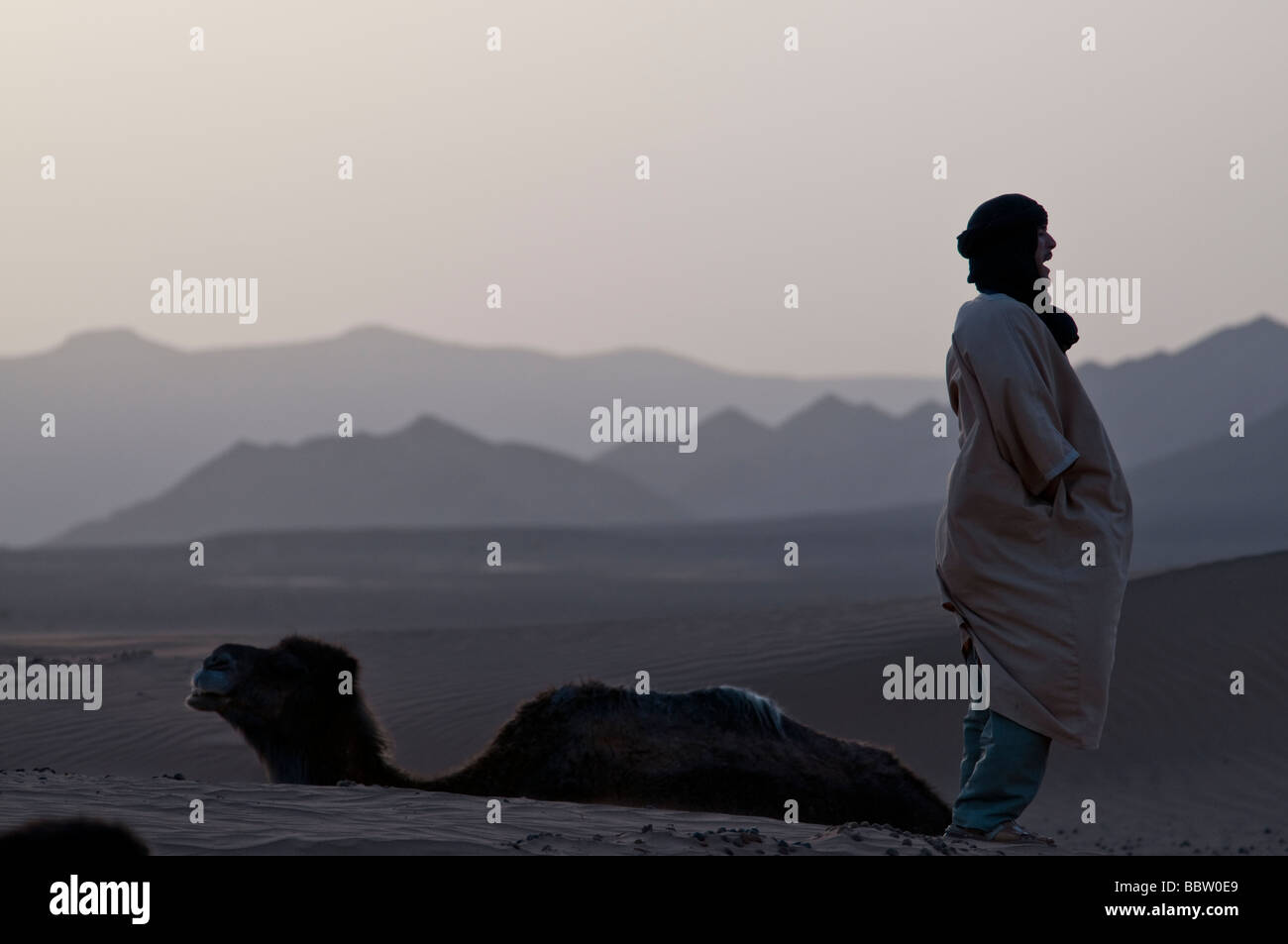 Ein Berber grüßt den Sonnenaufgang über der Wüste von Südmarokko Stockfoto