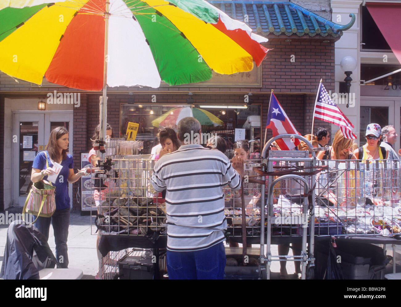 Straßenverkäufer in New York. New York City, Canal Street, Lower East Side Street Verkaufsstand. Puerto-ricanische und amerikanische Flagge. Farbenfroher Regenschirm Stockfoto