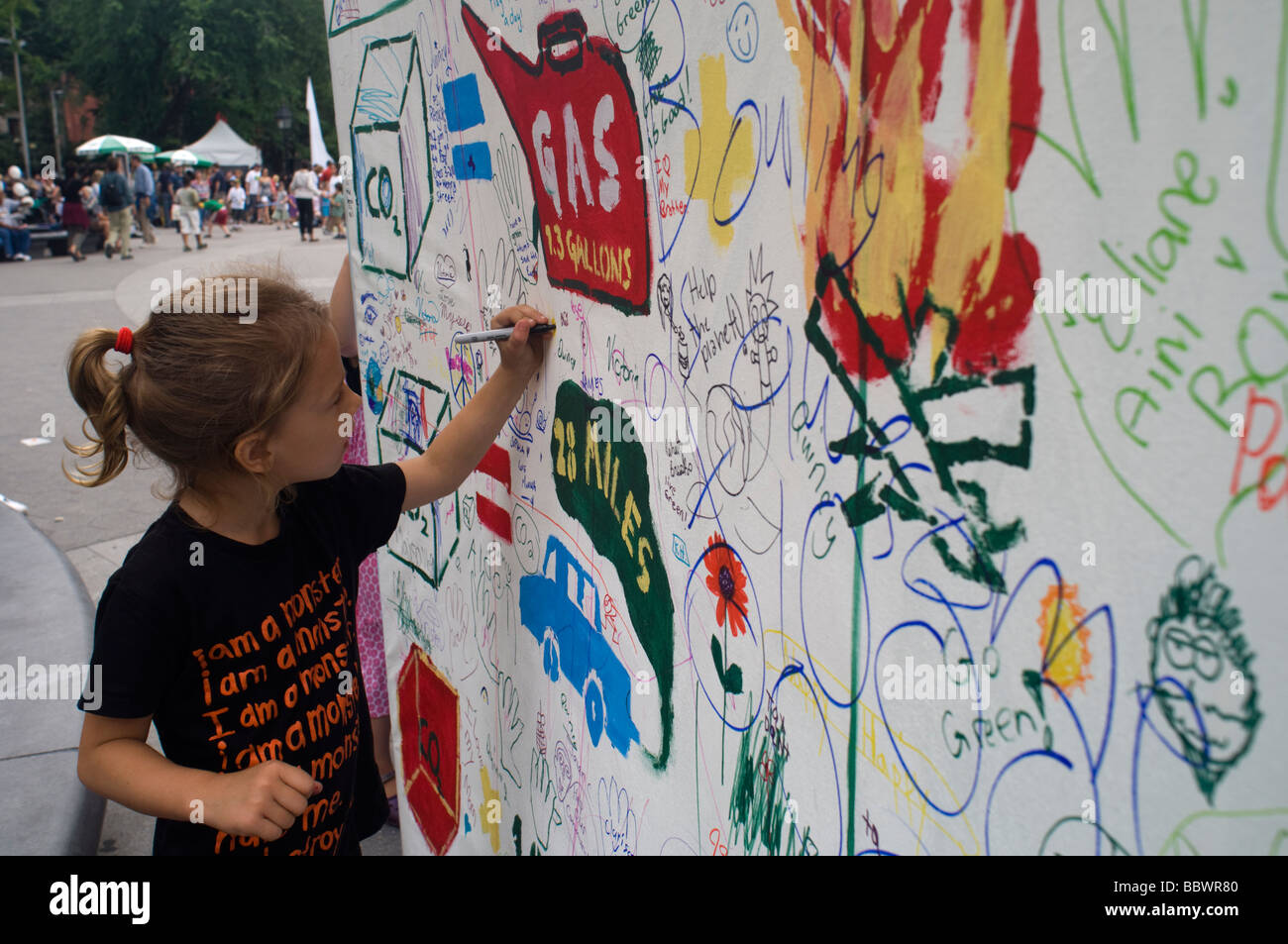 Ein Besucher der World Science Festival Street Fair schreibt ihre Gedanken auf die Umwelt auf einem riesigen Wandgemälde in Washington Square Stockfoto