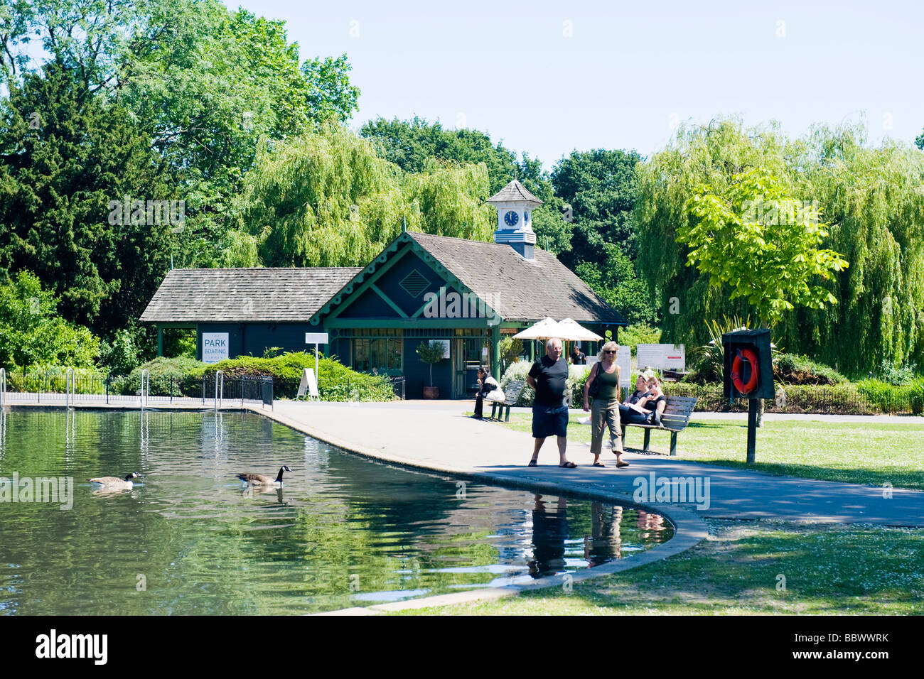 London, Regents Park, friedliche Szene der Childrens See mit Booten mit zwei kanadische Gänse & Café-Restaurant im Hintergrund Stockfoto