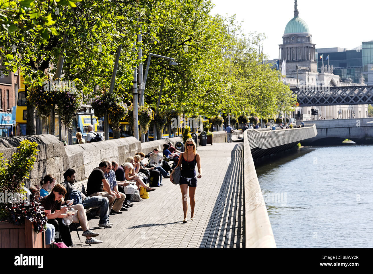 Leute sitzen in der Sonne auf der Liffey-Promenade am unteren Ormond Quay Central Dublin Irland Stockfoto