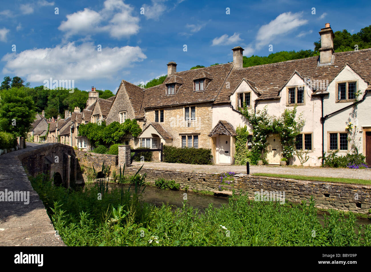 Malerischen Dorf von Castle Combe in voller Blüte, Cotswolds, England an einem feinen Sommertag mit Brücke und von Bach Fluss genommen Stockfoto