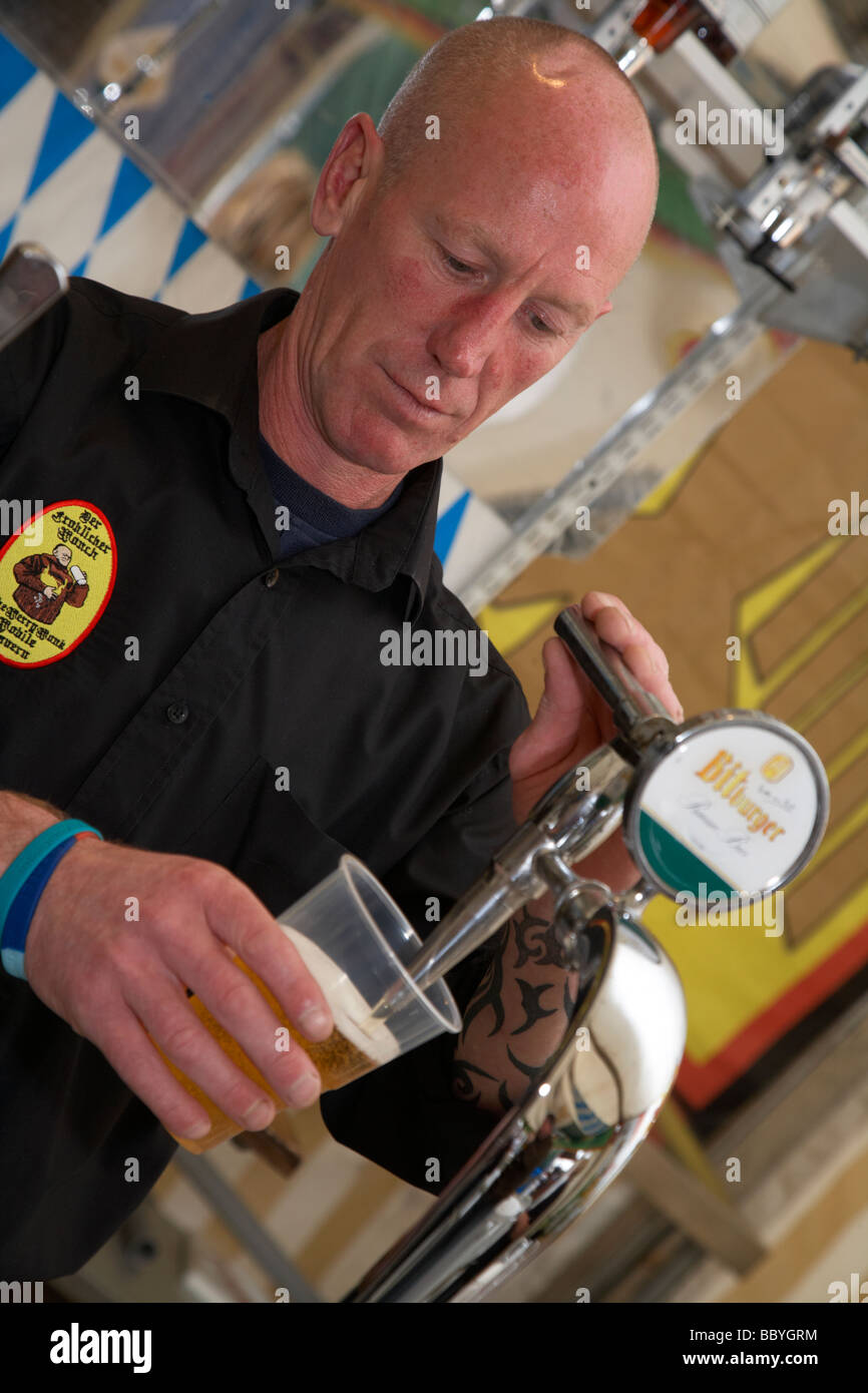Barkeeper gießen ein Bier in einem Plastikbecher in eine Nachahmung deutsches Bier-Stall im Vereinigten Königreich Stockfoto