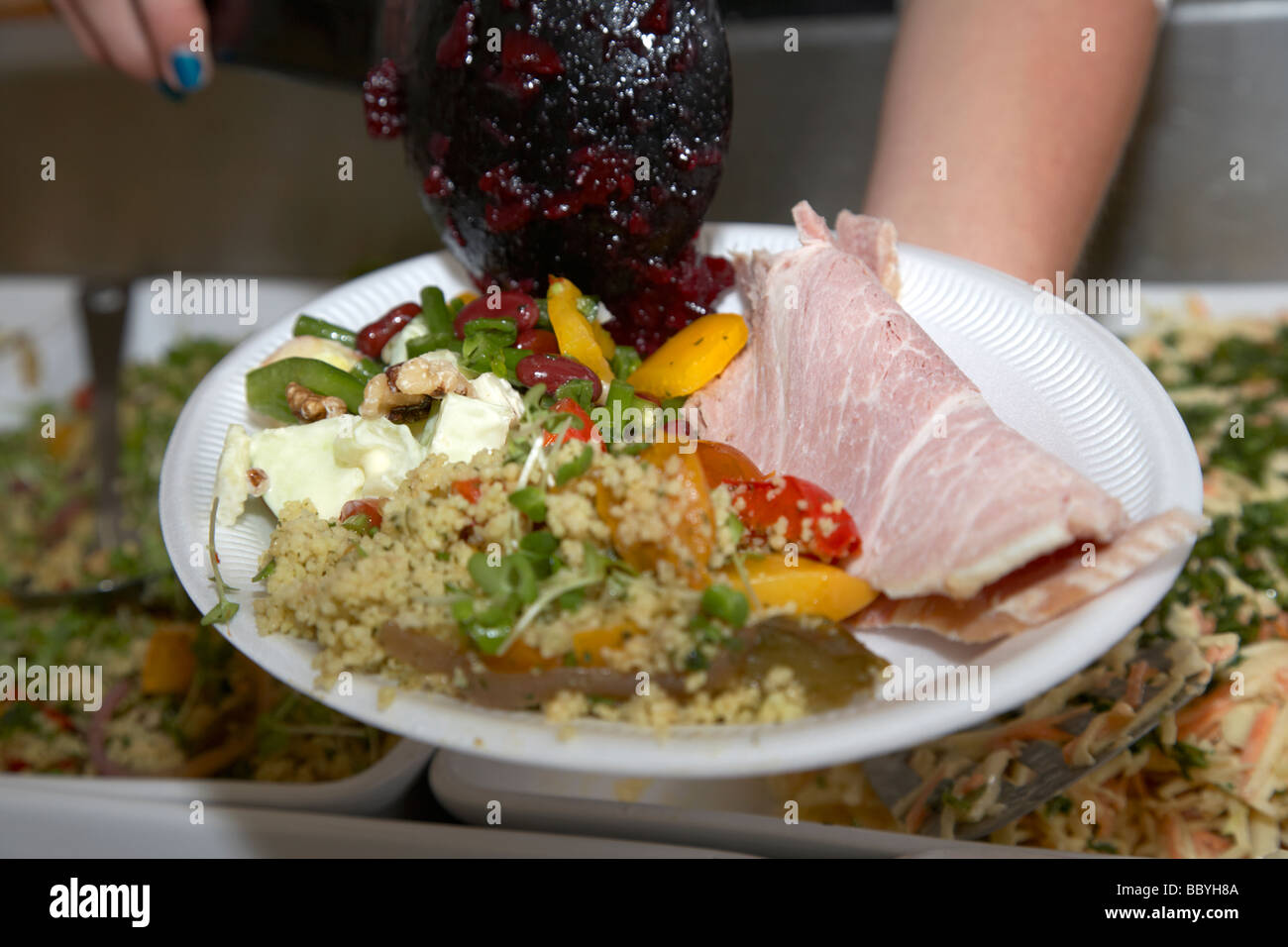 Frau Lieferanten Platzierung Schinken Salat Verschiedenes auf eine Styropor Platte an einen Lebensmittelmarkt im Vereinigten Königreich Stockfoto