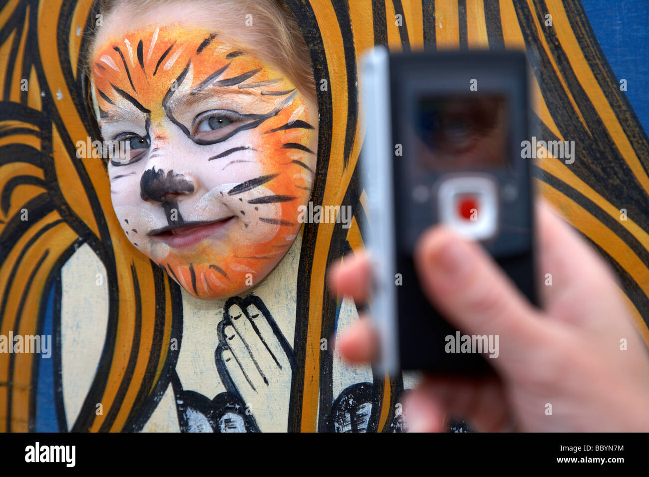 Fünf Jahres altes Mädchen mit Gesicht gemalt haben ihr Foto von ihrer Mutter mit einem Mobiltelefon im Vereinigten Königreich Stockfoto