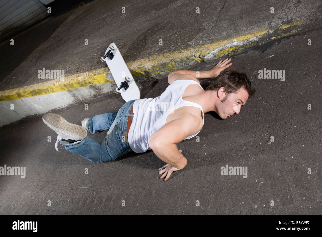 Skateboarder auf Asphalt in eine seltsame Position liegend Stockfoto