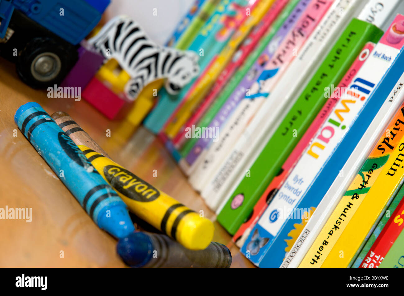 Kinderbücher in einer Gärtnerei mit Buntstiften im Vordergrund... Die Bücher sind zweisprachig, Englisch-Walisisch. Stockfoto