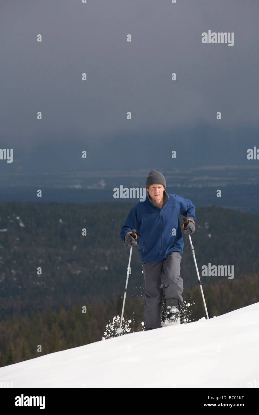 Ein Solo männlich Schneeschuhwanderer macht seinen Weg auf einen Berg. Stockfoto