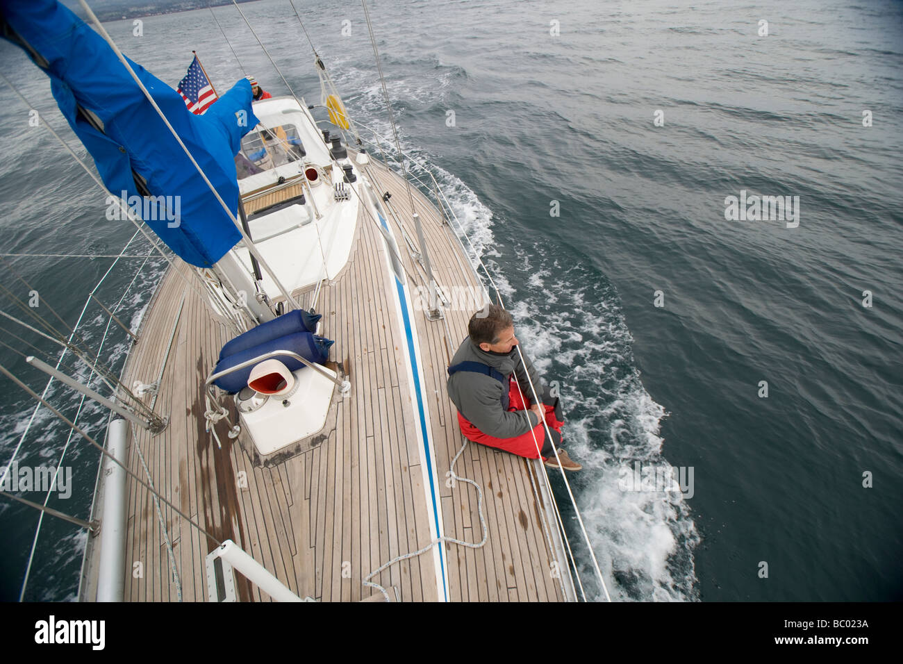 Ein Mann auf dem Deck von seinem Segelboot hängen. Stockfoto
