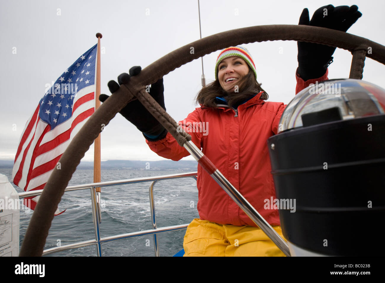 Eine Frau lächelt beim Lenken eines Segelbootes. Stockfoto