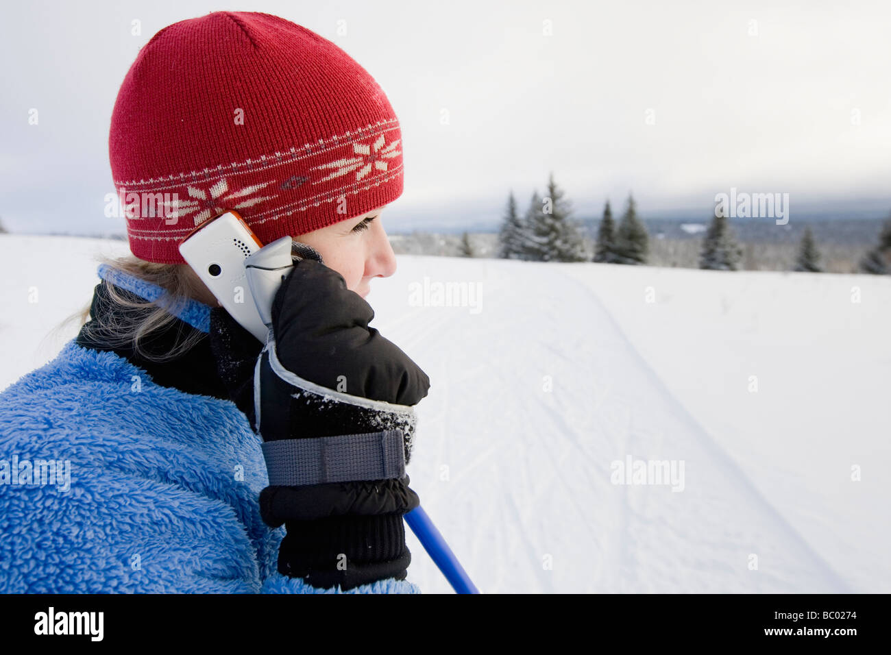 Eine junge Frau auf einem Handy beim Langlaufen im Gespräch. Stockfoto
