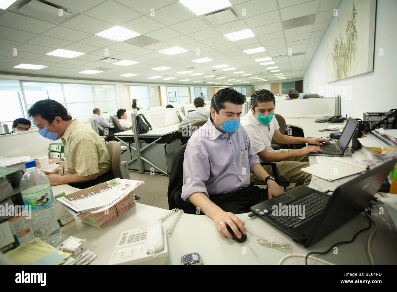 Manche Menschen arbeiten an ihren Computern mit Masken in einem Büro während der Schweinegrippe-Epidemie in Mexiko-Stadt, DF, Mexiko. Stockfoto