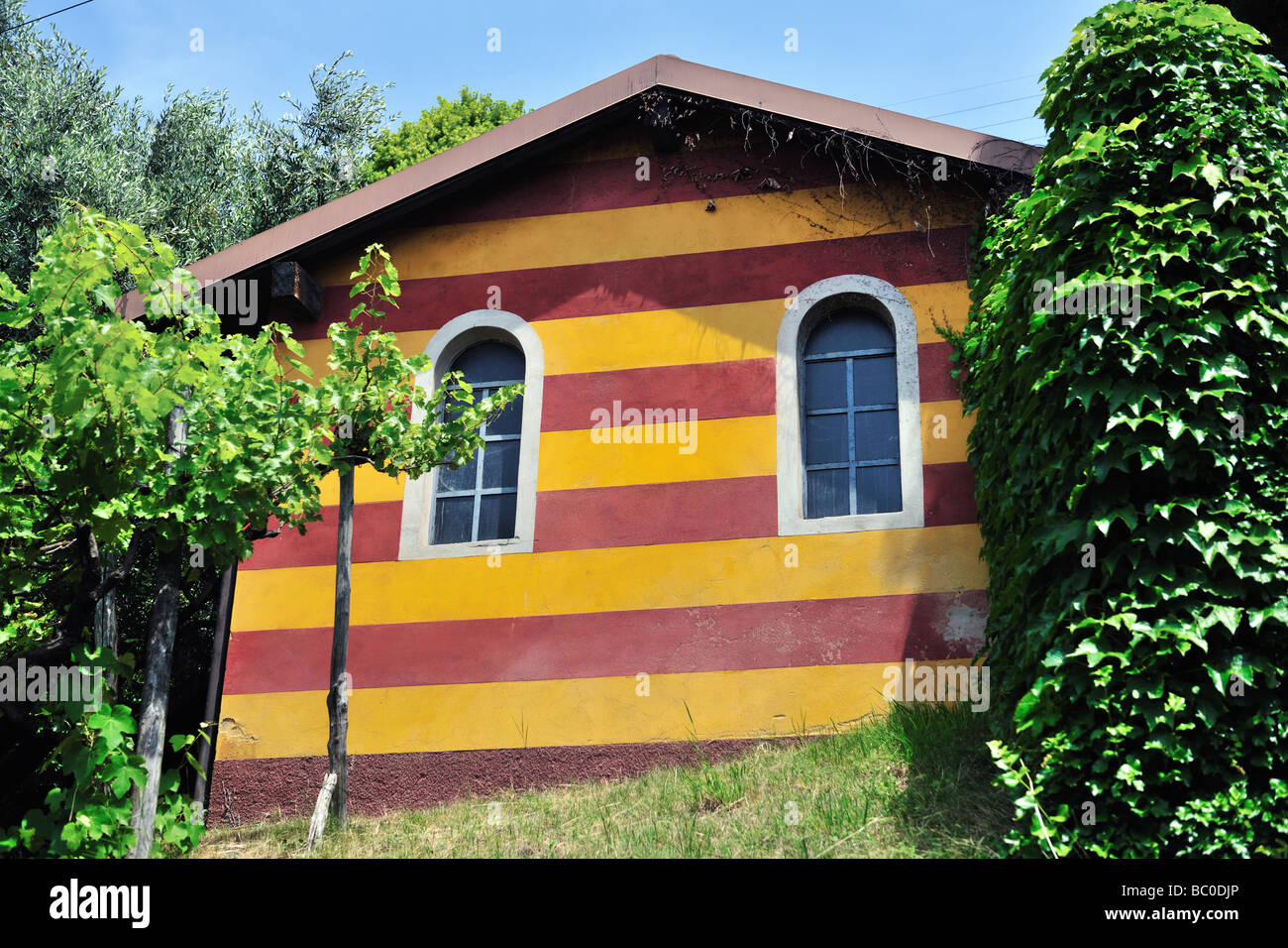 Roter Ocker und gelb gestreiften Nebengebäude mit zwei Rundbogenfenster in Lombardei-Italien Stockfoto