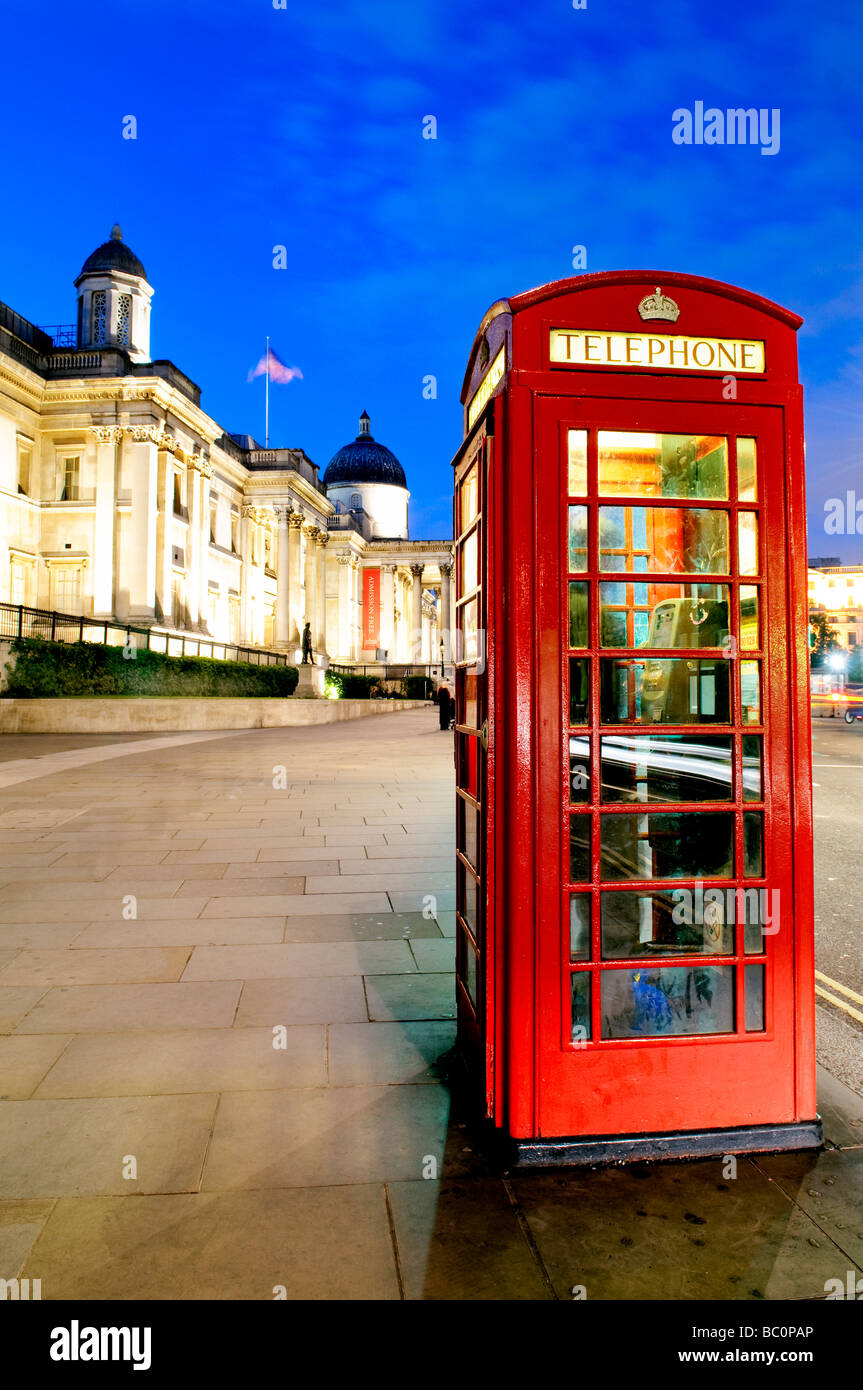Rote Telefonzellen in der Nacht neben dem Trafalgar Square, London, mit der Nationalgalerie im Hintergrund auf der linken Seite. Stockfoto