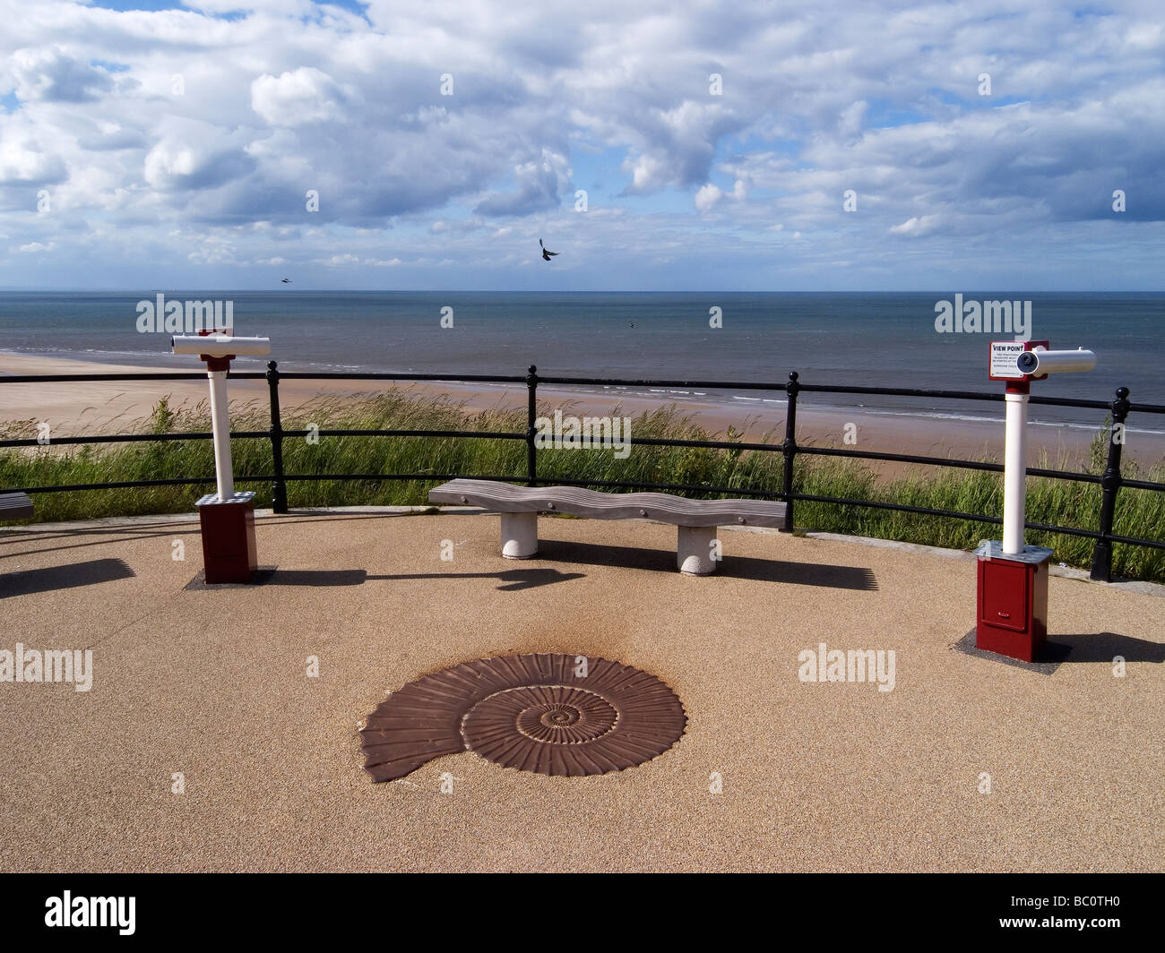 Zwei am Meer Teleskope auf der Promenade am Saltburn am Meer mit einem Gusseisen-Nachbau eines Ammoniten Fossil Stockfoto
