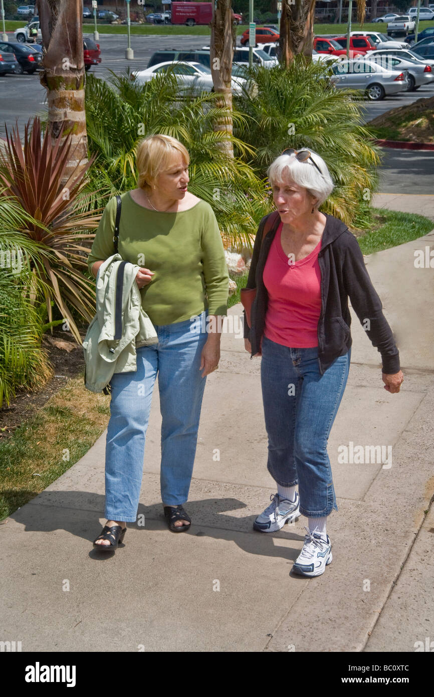 Zwei Freundinnen mittleren Alters gehen und unterhalten sich im Freien in Dana Point CA Stockfoto
