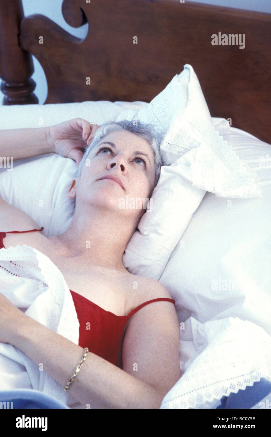 Schlaflose Reife Frau im Bett hellwach Stockfoto