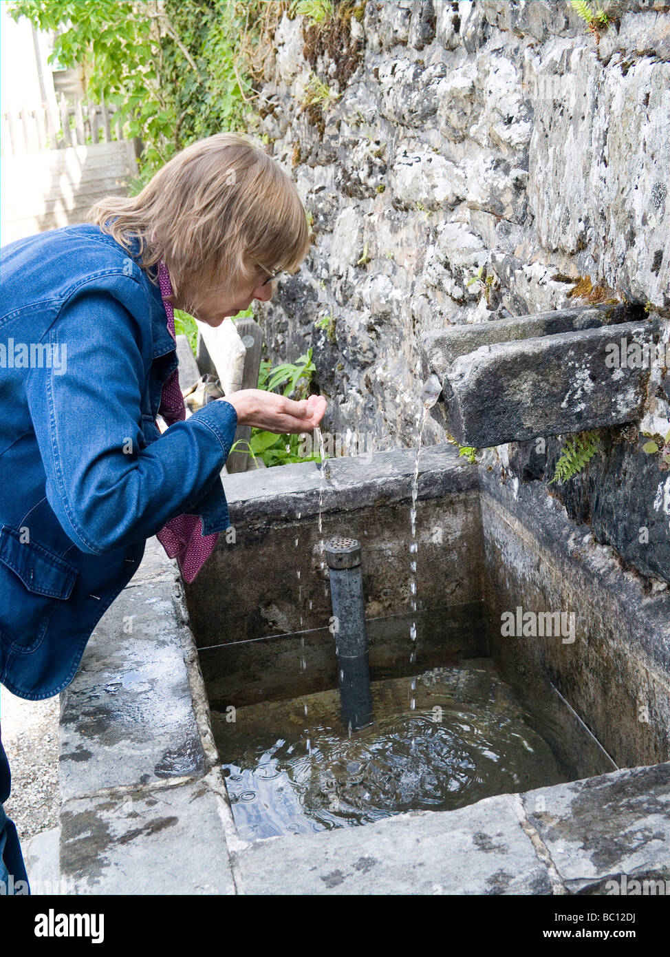 Eine Frau trinkt heiliges Wasser aus der Quelle in Heiligwasser in der Nähe von Innsbruck Österreich Stockfoto