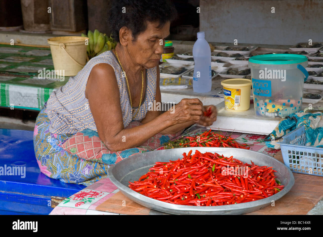 Alte Dame in thailändischen Markt Vorbereitung Chilischoten zu verkaufen Stockfoto