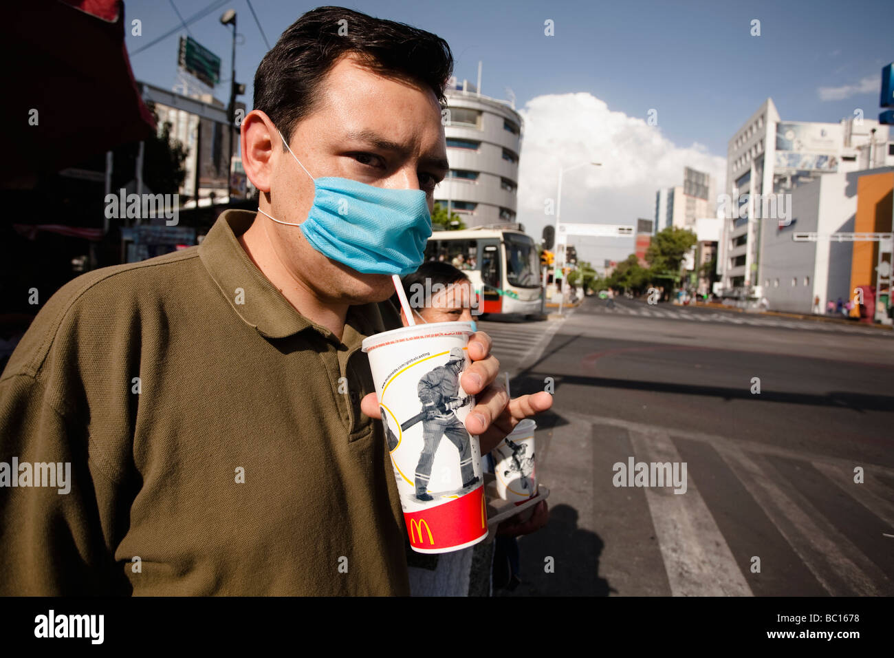 Eine Mann auf der Straße trinkt aus einem McDonalds Cup durch eine blaue Maske während der Schweinegrippe-Epidemie in Mexiko-Stadt. Stockfoto