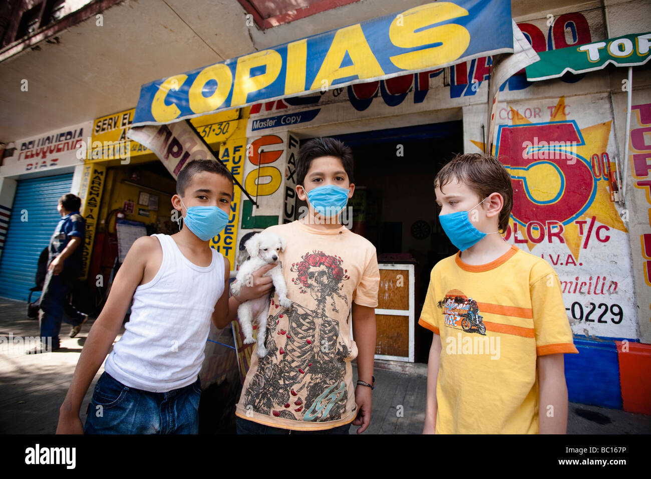 Drei Kinder tragende Masken halten einen kleinen Welpen auf der Straße während der Schweinegrippe-Epidemie in Mexiko-Stadt, DF, Mexiko. Stockfoto