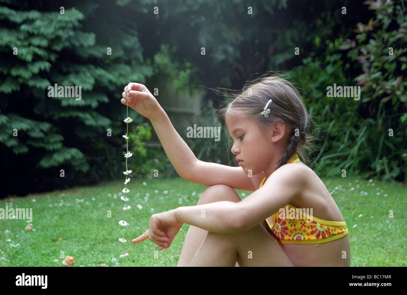 Kleines Mädchen zählen die Blumen in ihrem Daisy-chain Stockfoto