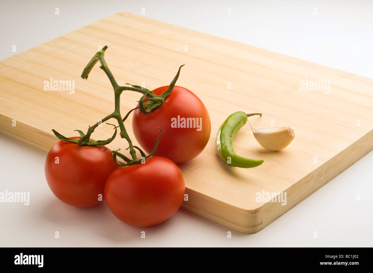 Eine Reihe von Tomaten, Knoblauch und Chili auf ein Schneidbrett aus Holz gelegt. Stockfoto