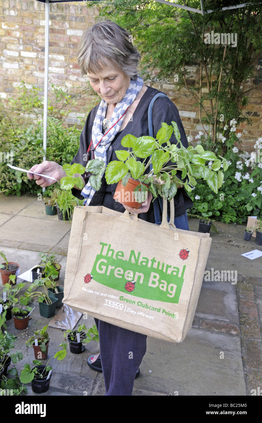 Elegante Dame mit The Natural Green Bag und tragenden Pflanzen im Garten Stockfoto