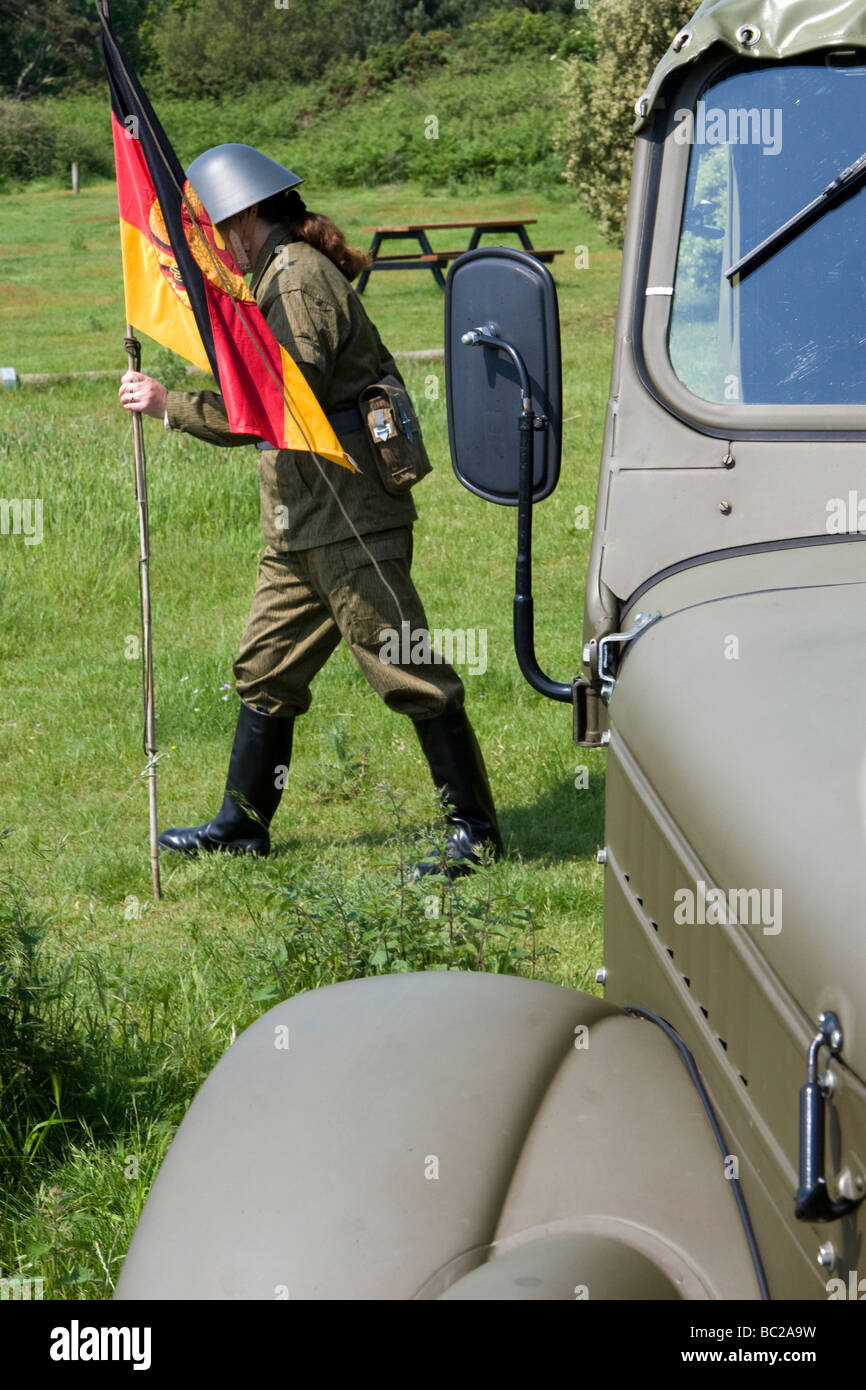 Junge Frau in uniform NVA hält die DDR Fahne von einem Vaz-Armee-Lastwagen Stockfoto